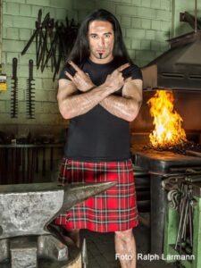 Bülent Ceylan in Schottenrock in Metalpose mit Pommesgabel-Händen